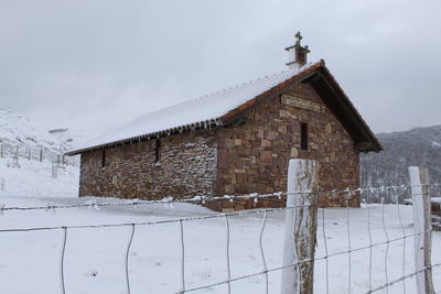 View of cottage on snow covered building against sky