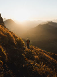 Rear view of man standing on mountain against sky