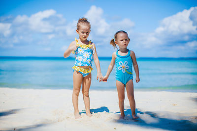 Full length of children on beach against sky