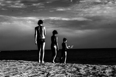 Men standing on beach against sky