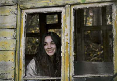 Portrait of smiling young woman against window