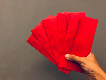 Close-up of hand holding red umbrella against wall