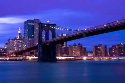 Illuminated bridge over river at night