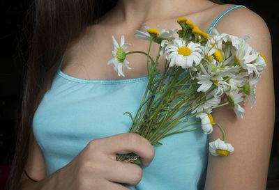 Midsection of woman holding daisies
