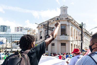 Rear view of people in front of buildings against sky