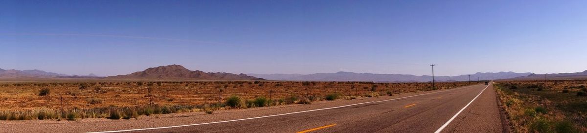 Road amidst landscape against clear blue sky