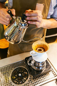 Midsection of barista preparing coffee in cafe