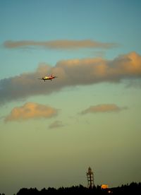 Low angle view of airplane flying against sky during sunset