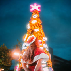 Rear view of woman standing against sky at night