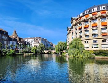 Buildings by river against sky