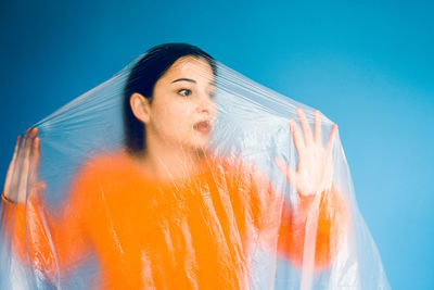 Woman covered in plastic standing against blue background