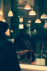 Woman looking at illuminated pendant lights on window display