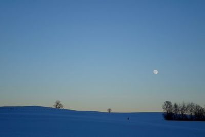 Scenic view of snow covered field against clear sky at dusk