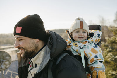 Smiling father carry toddler daughter in carrier