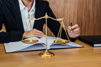 Midsection of judge writing in book on table