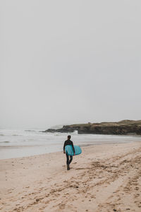 Rear view of man on beach against clear sky