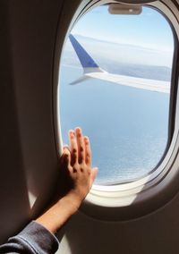 Cropped image of person hand on airplane window