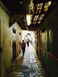 Rear view of woman walking on narrow alley