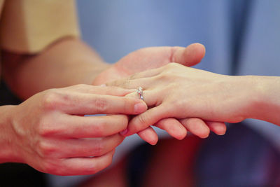 Cropped image of wedding couple exchanging finger rings during ceremony