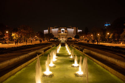 Illuminated bridge over canal in city at night