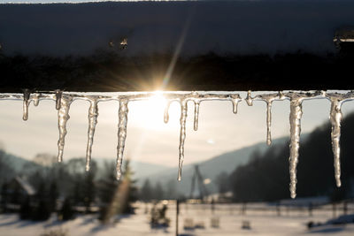 Close-up of water drops on snow against sky during sunset