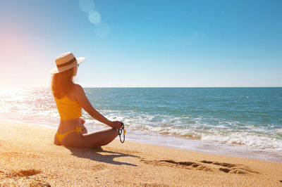 Rear view of woman sitting at beach