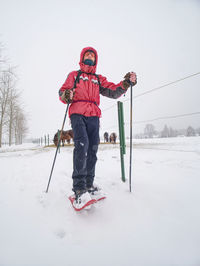 Winter hiking in mountains on snowshoes with a backpack. hiker walk around fence of horse paddock.