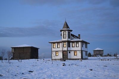 House on snow covered field against sky