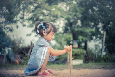 Side view of girl playing with dirt on field