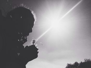 Low angle view of sun shining through clouds