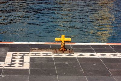 High angle view of cross on footpath by sea