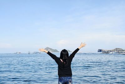 Rear view of person standing in sea against sky