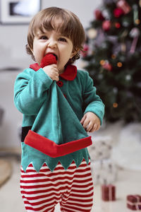 A little 12-month-old christmas elf with a christmas tree and gifts