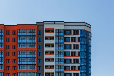 New high rise apartment building with many balcony and windows on blue sky with clouds background