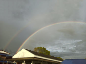Low angle view of rainbow over building against sky