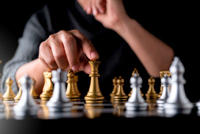 Midsection of man playing chess against black background