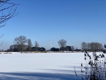 Snow covered field against clear blue sky