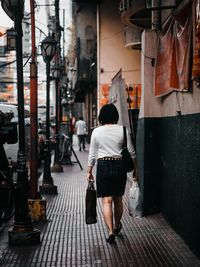 Rear view of woman walking on footpath in city