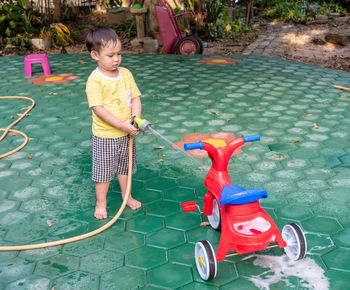 High angle view of boy washing tricycle outdoors