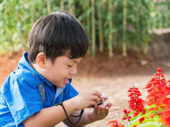 Boy photographing flowers with camera at park