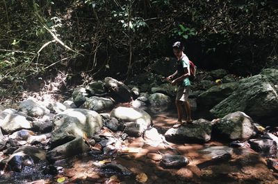 Young woman standing on rock in forest