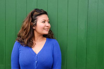 Portrait of smiling young woman against green wall