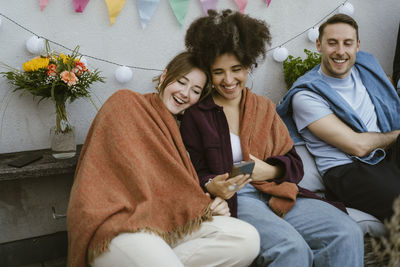 Portrait of smiling friends sitting on sofa at home