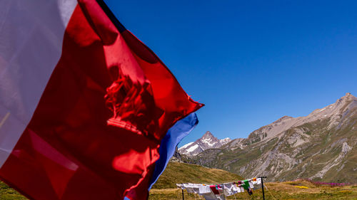 Red flag on mountain against blue sky