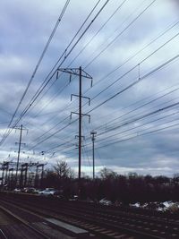 Low angle view of power lines against cloudy sky