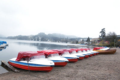 Boats moored in lake against clear sky