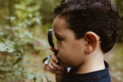 Boy looking at plants through magnifying glass