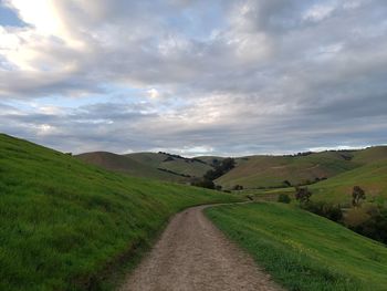 Scenic view of road amidst field against sky