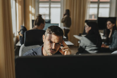 Tired businessman working with colleagues at office