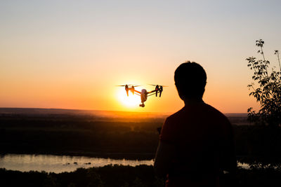 Rear view of silhouette man standing against sky during sunset